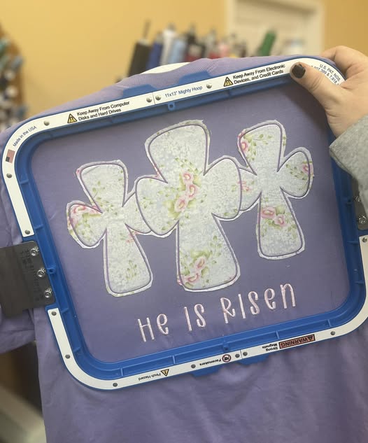 He is Risen Embroidered on a Lavender Port & Co Soft Style T-shirt